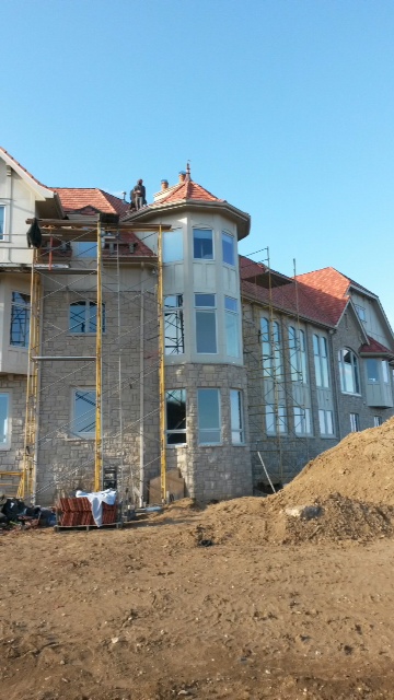 Large house under construction with scaffolding and workers.