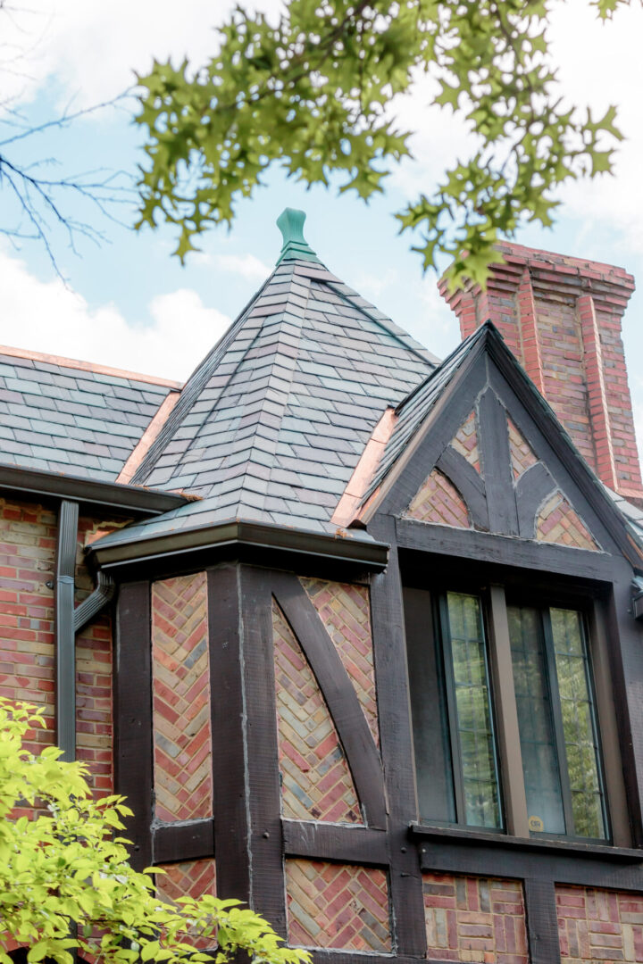 Tudor-style roof with detailed brick chimney and leaded glass windows.