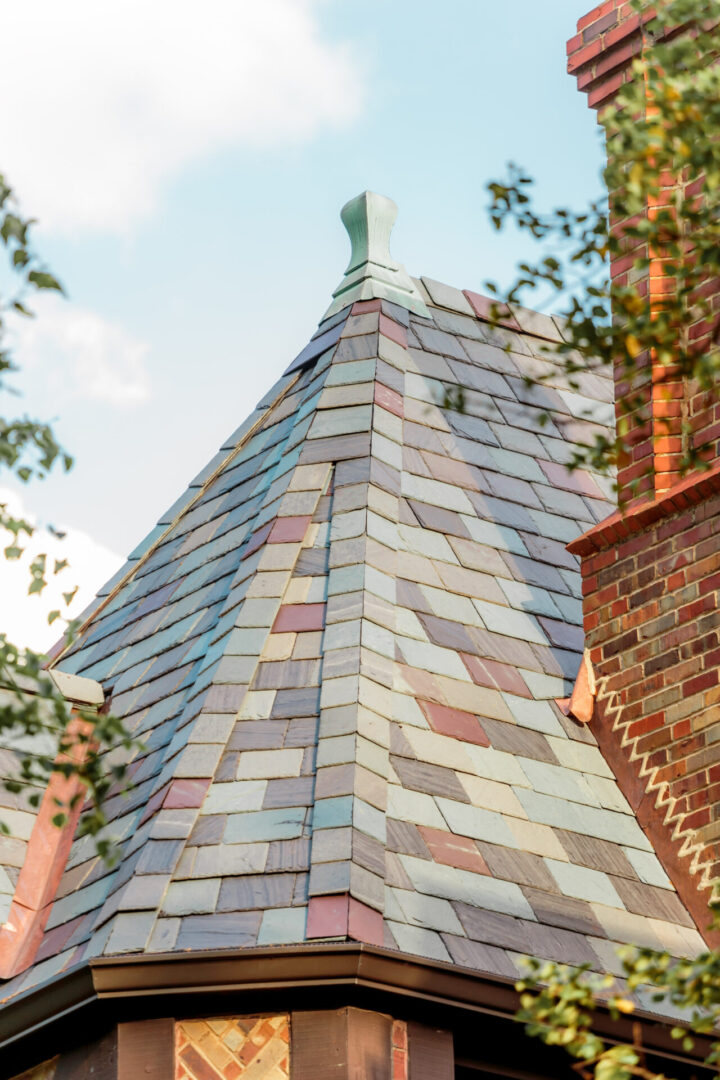 Close-up of a slate-tiled roof with a decorative finial on top.