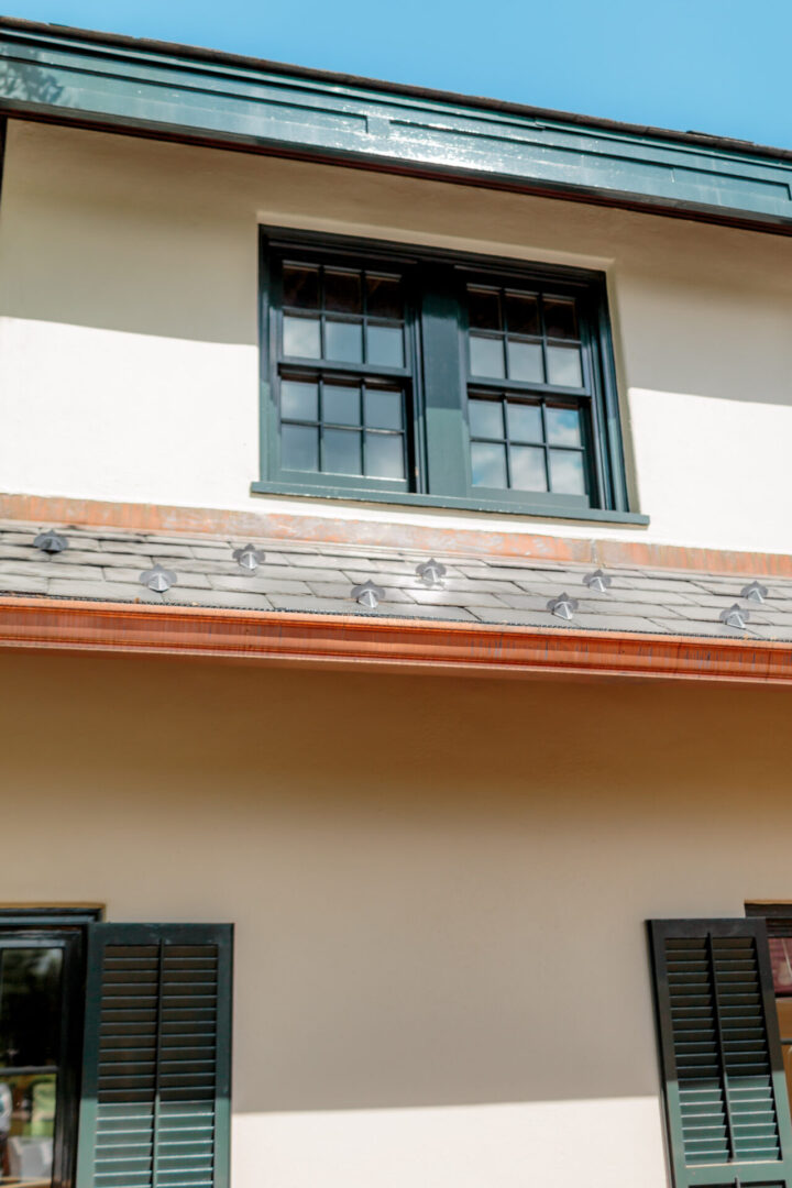 Window frame with a wooden decorative panel below it on a light-colored wall.
