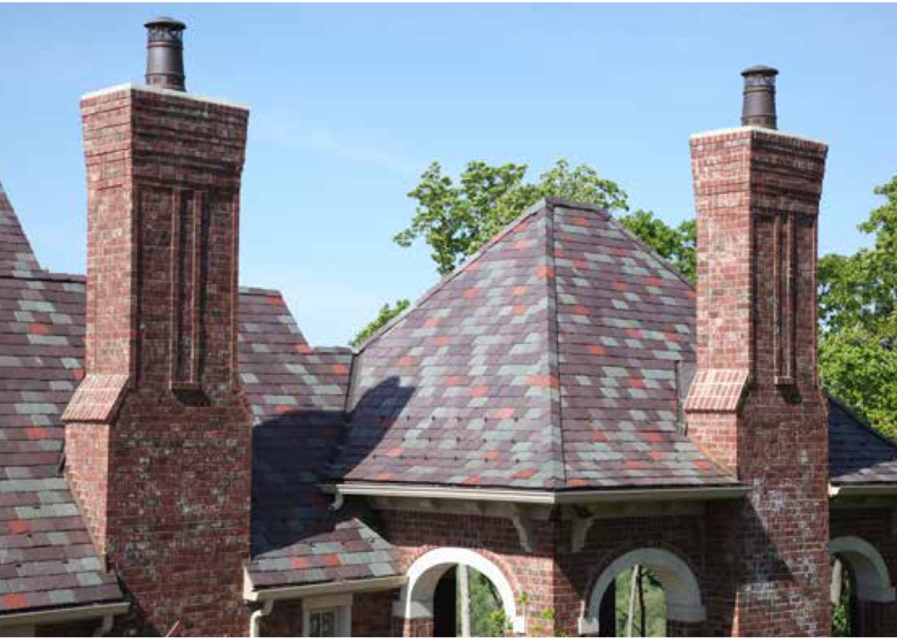 Roof with colorful shingles and two brick chimneys.