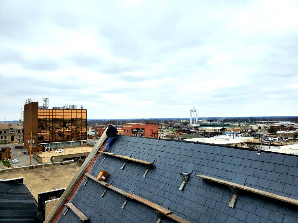 View of rooftops and construction materials under a cloudy sky.
